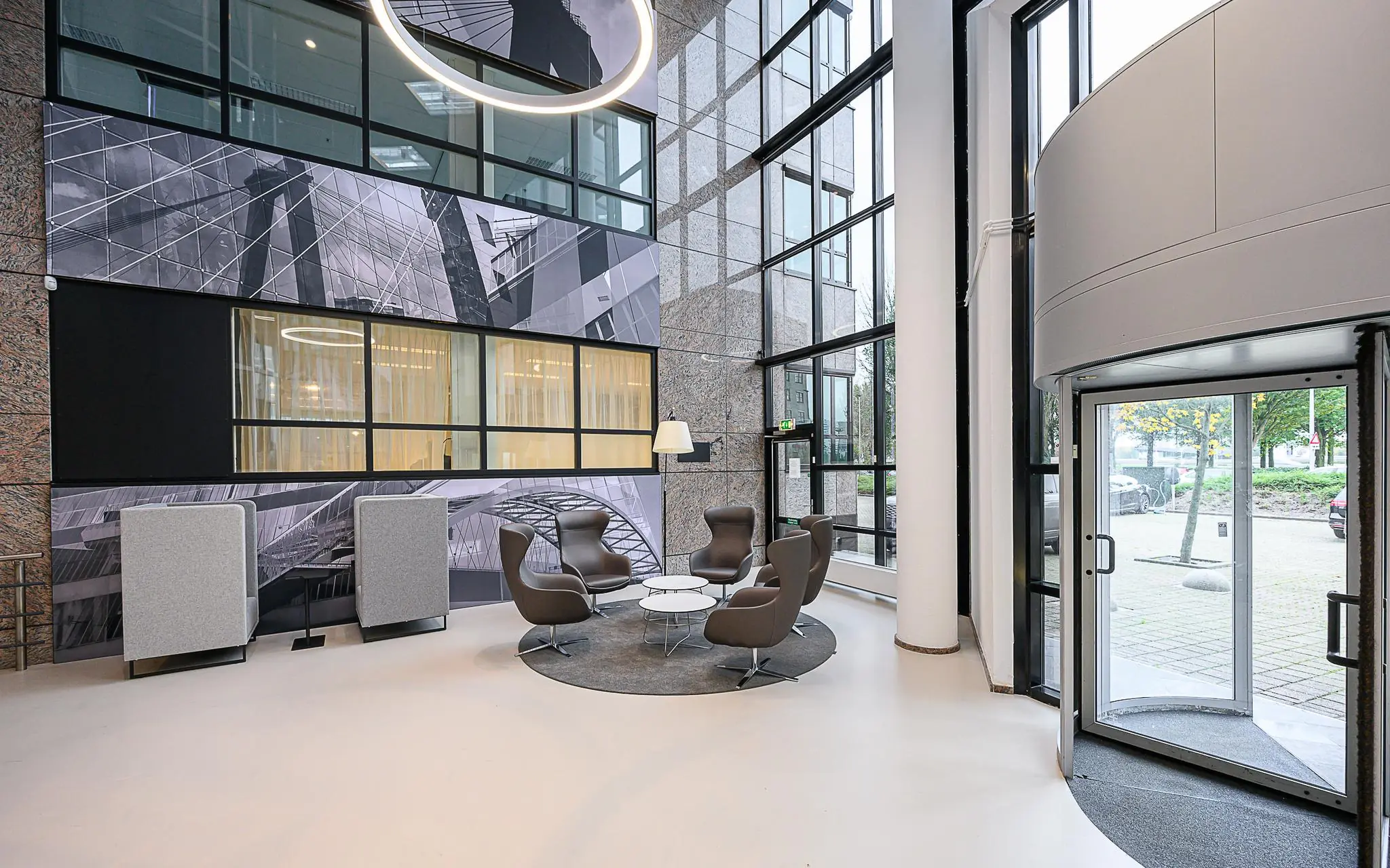 Moderne ontvangsthal van het Rivium Quadrant met designstoelen, glazen gevel en kunstzinnige wanddecoratie.